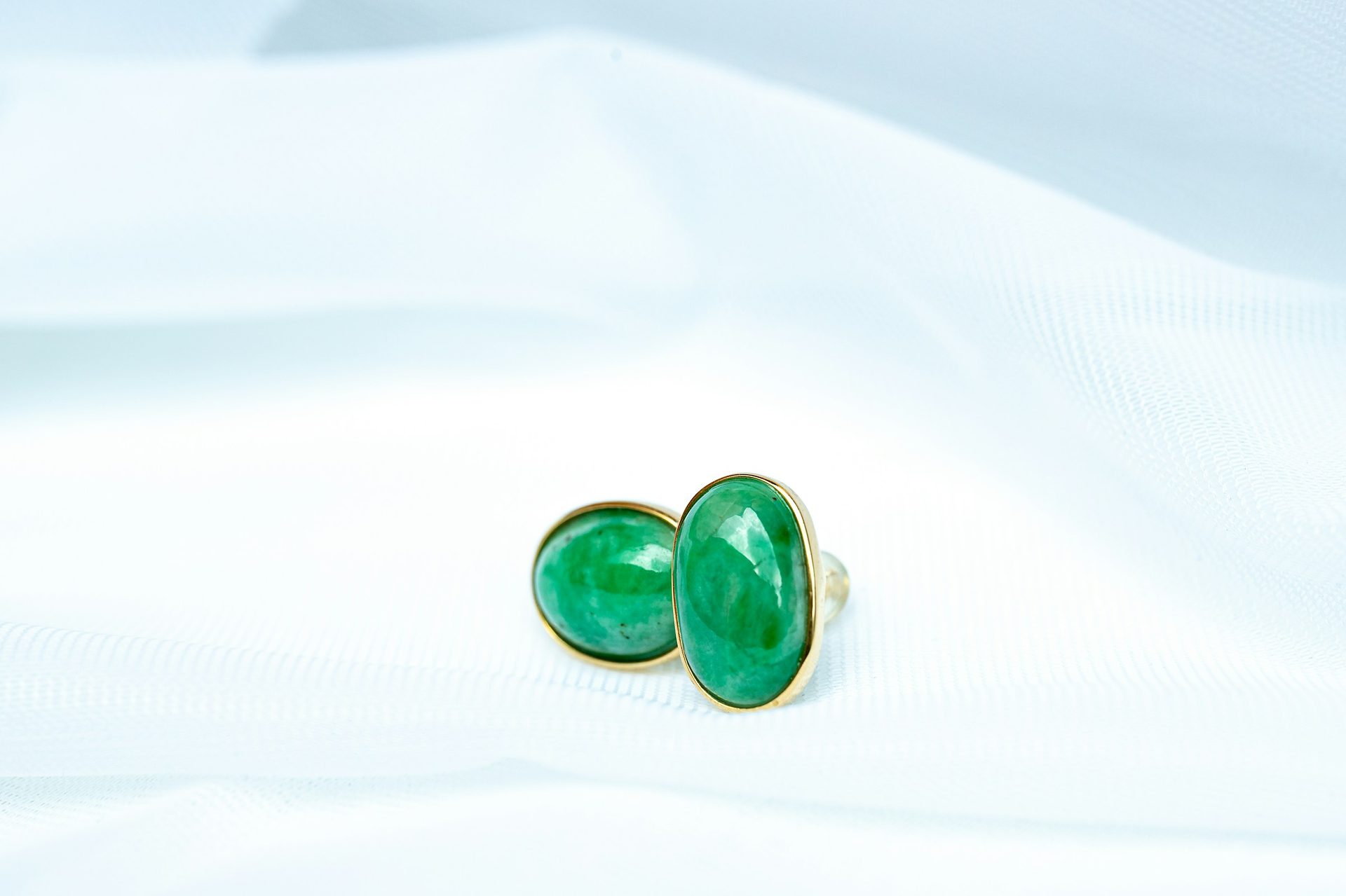 Cat's Eye Emerald cabochon showing silver chatoyant band on vivid green background