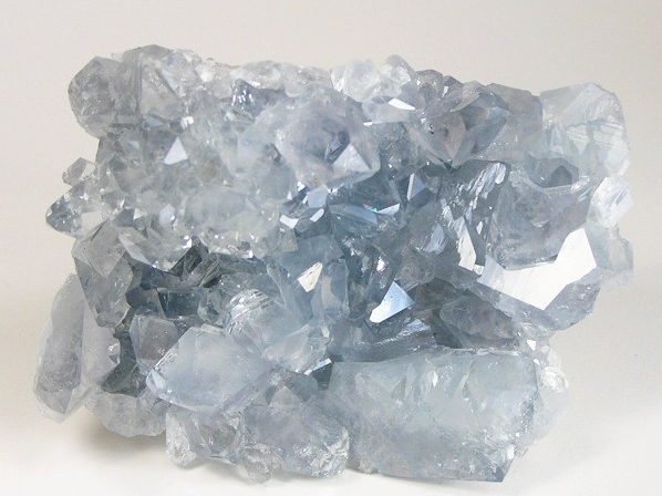 Celestite cluster showing pale blue tabular crystals in geode cavity on white background