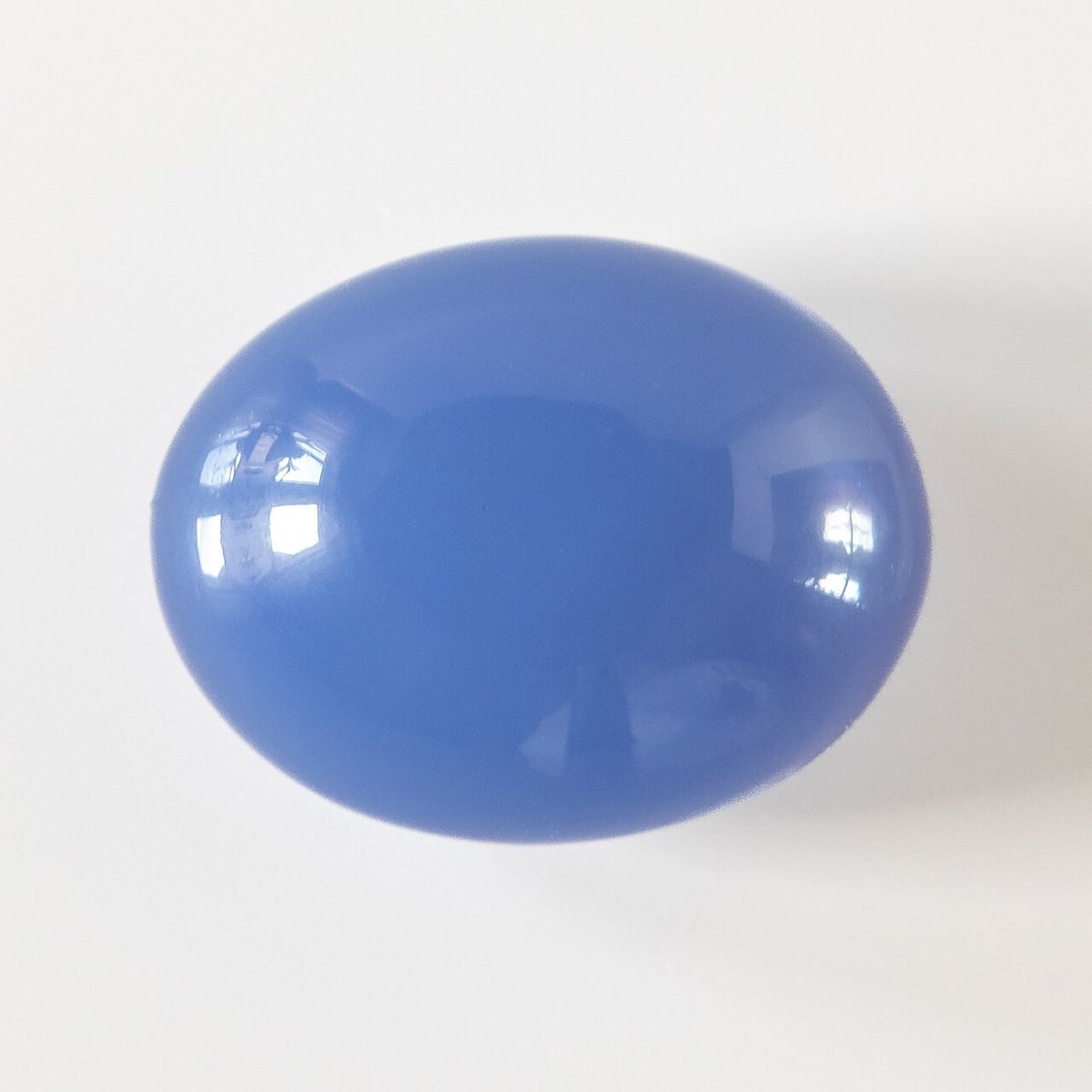 Polished blue chalcedony cabochon showing soft milky blue on neutral background