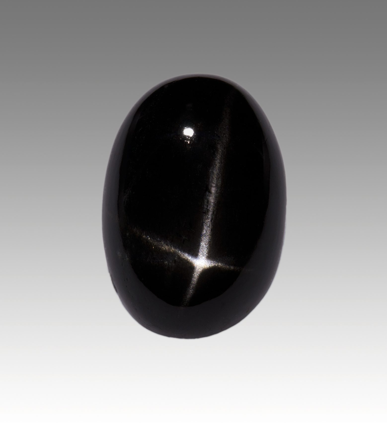 Diopside cat's eye cabochon showing white chatoyant ray across deep green pyroxene mineral