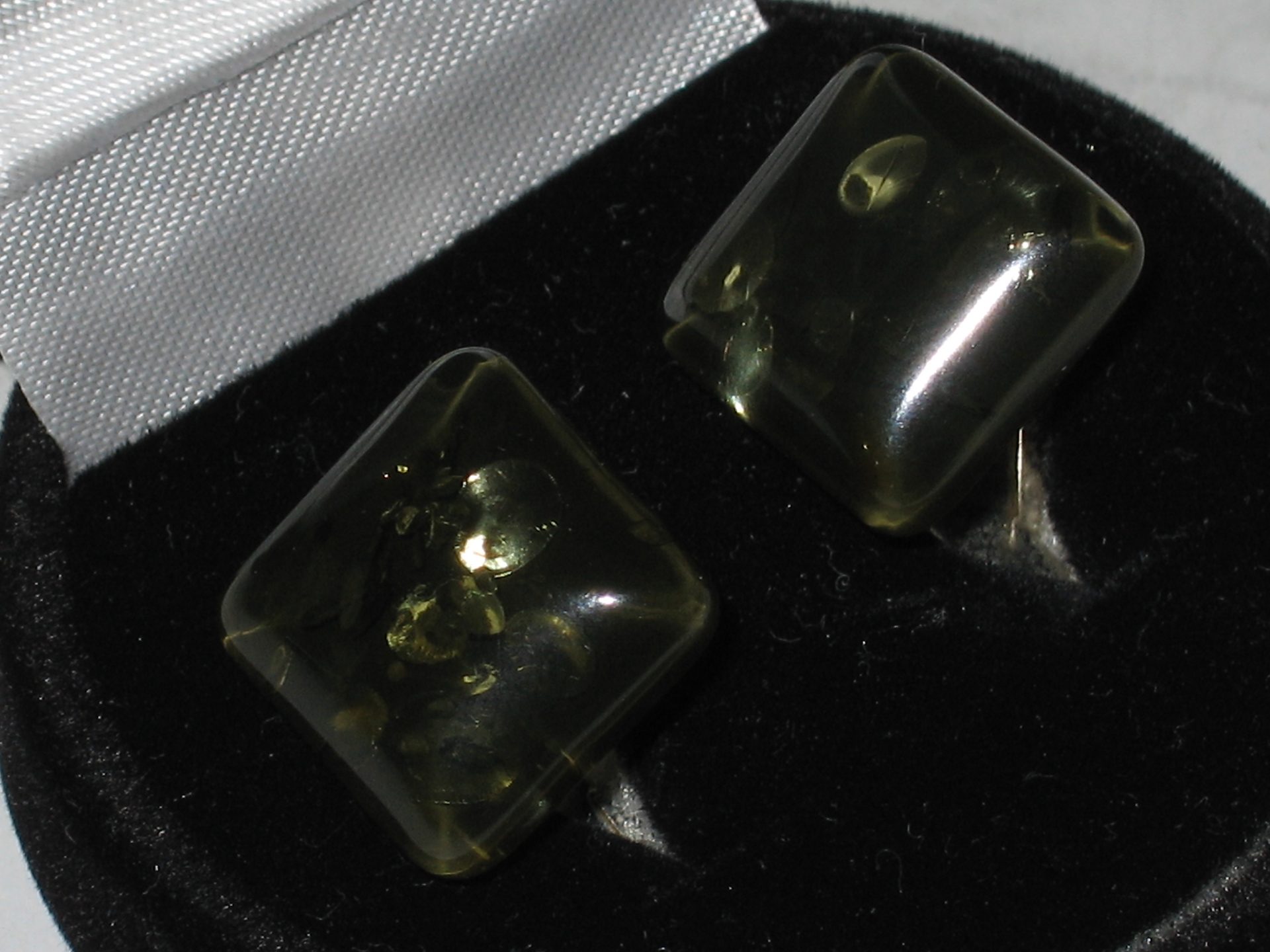 Polished green amber cabochon showing warm olive-green translucency on white background