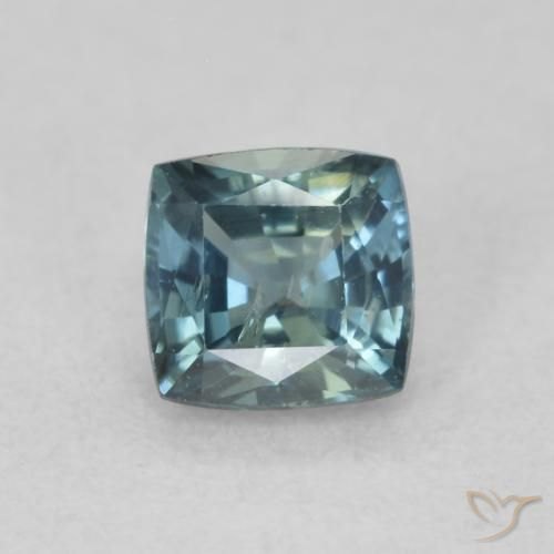 Polished hawk's eye cabochon showing chatoyant blue-gray bands on neutral background