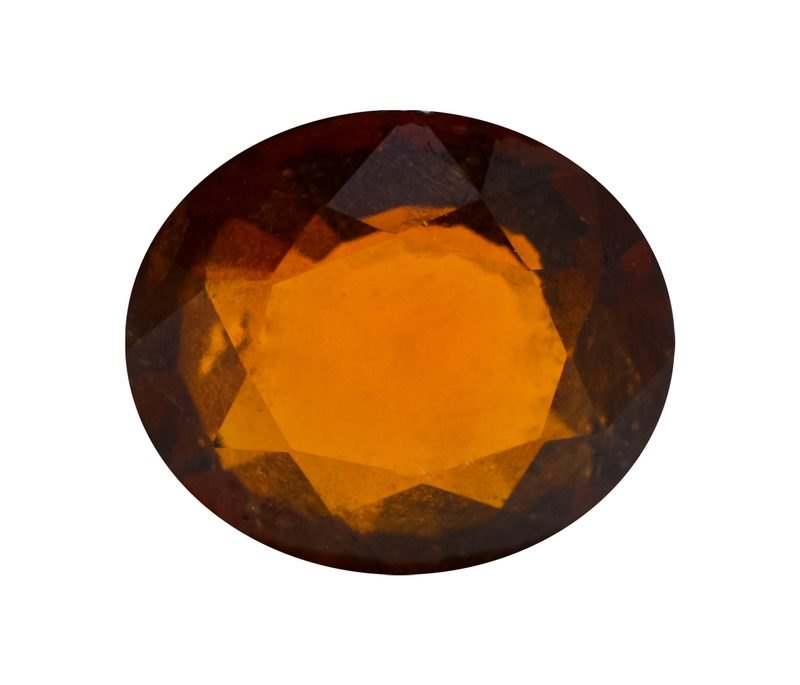 Faceted hessonite garnet showing cinnamon-orange color on neutral background