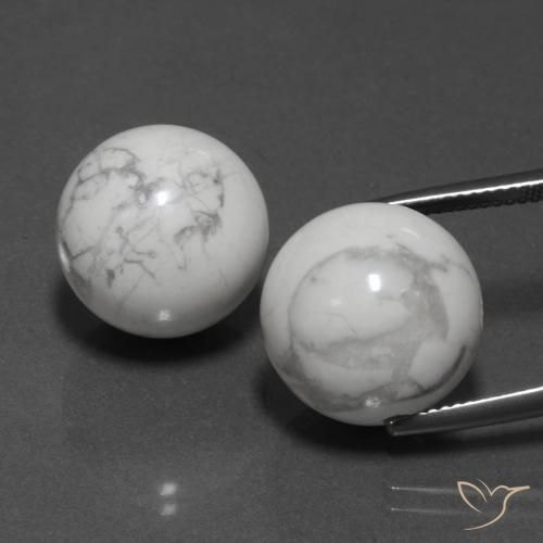 Tumbled white howlite cabochons showing characteristic gray marbled veining on neutral background