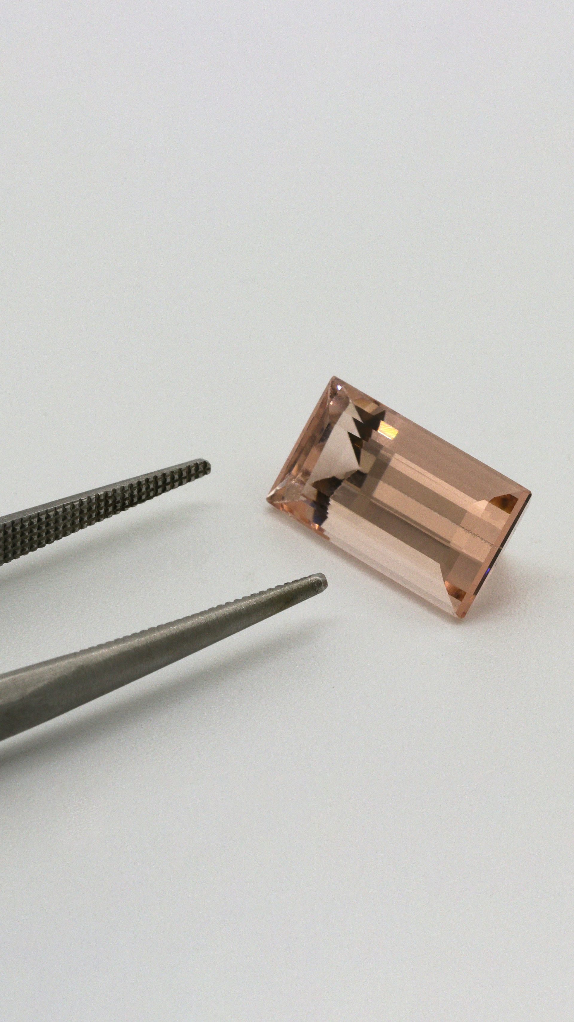 Faceted lab-created morganite gemstone showing soft peach-pink color on white background