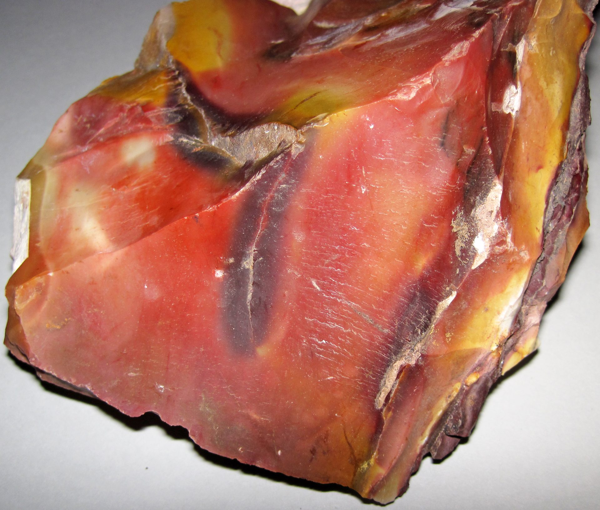 Mookaite jasper tumbled stone with swirling red yellow and purple colors on neutral background
