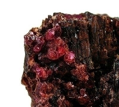 Faceted painite gemstone showing deep red-brown color on neutral background