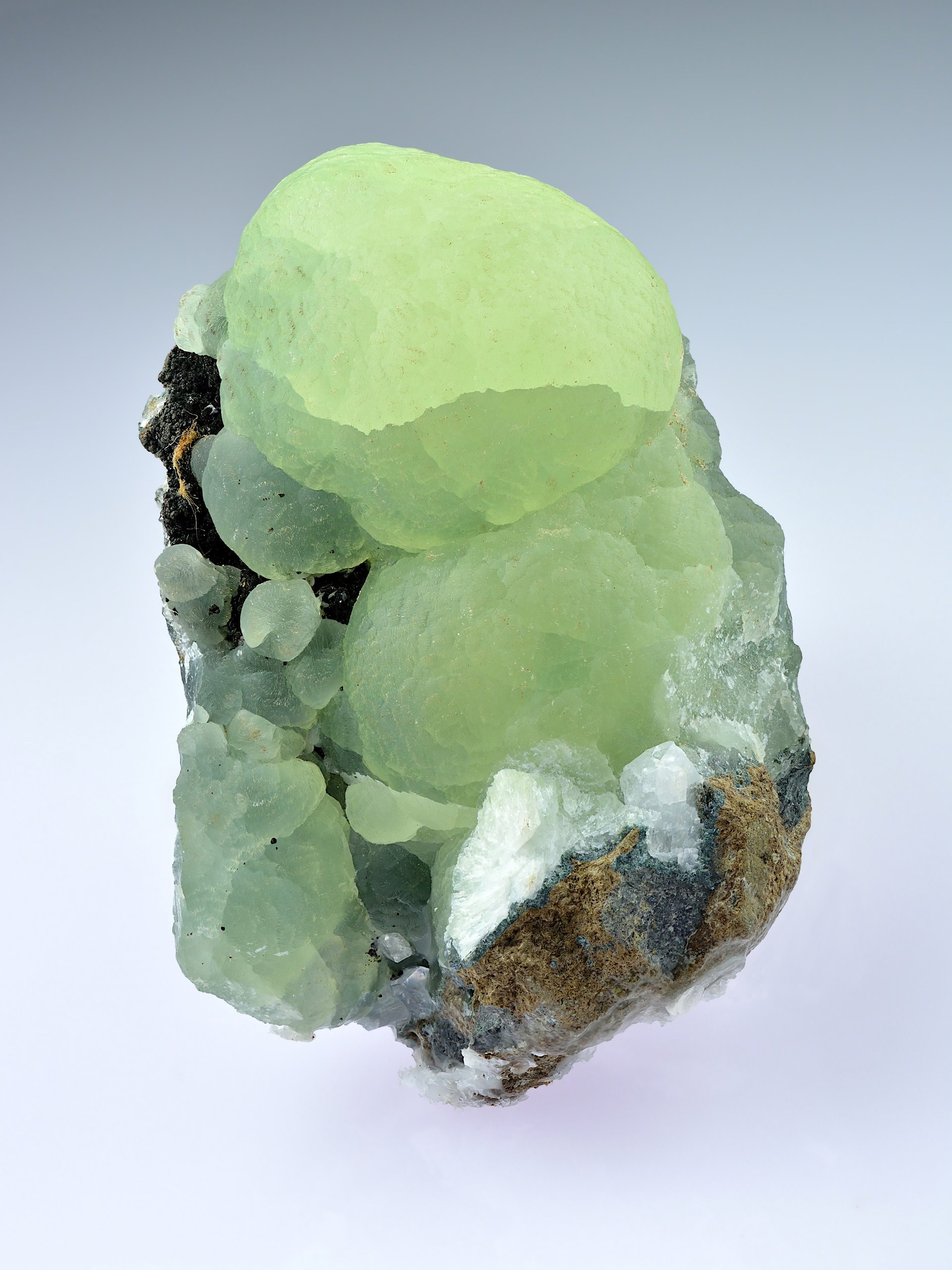 Polished prehnite cabochon showing translucent apple-green color on neutral background