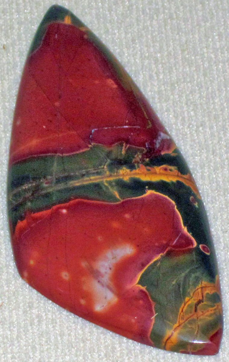 Red Creek Jasper slab showing swirling red, cream, brown, and gold patterns on polished surface