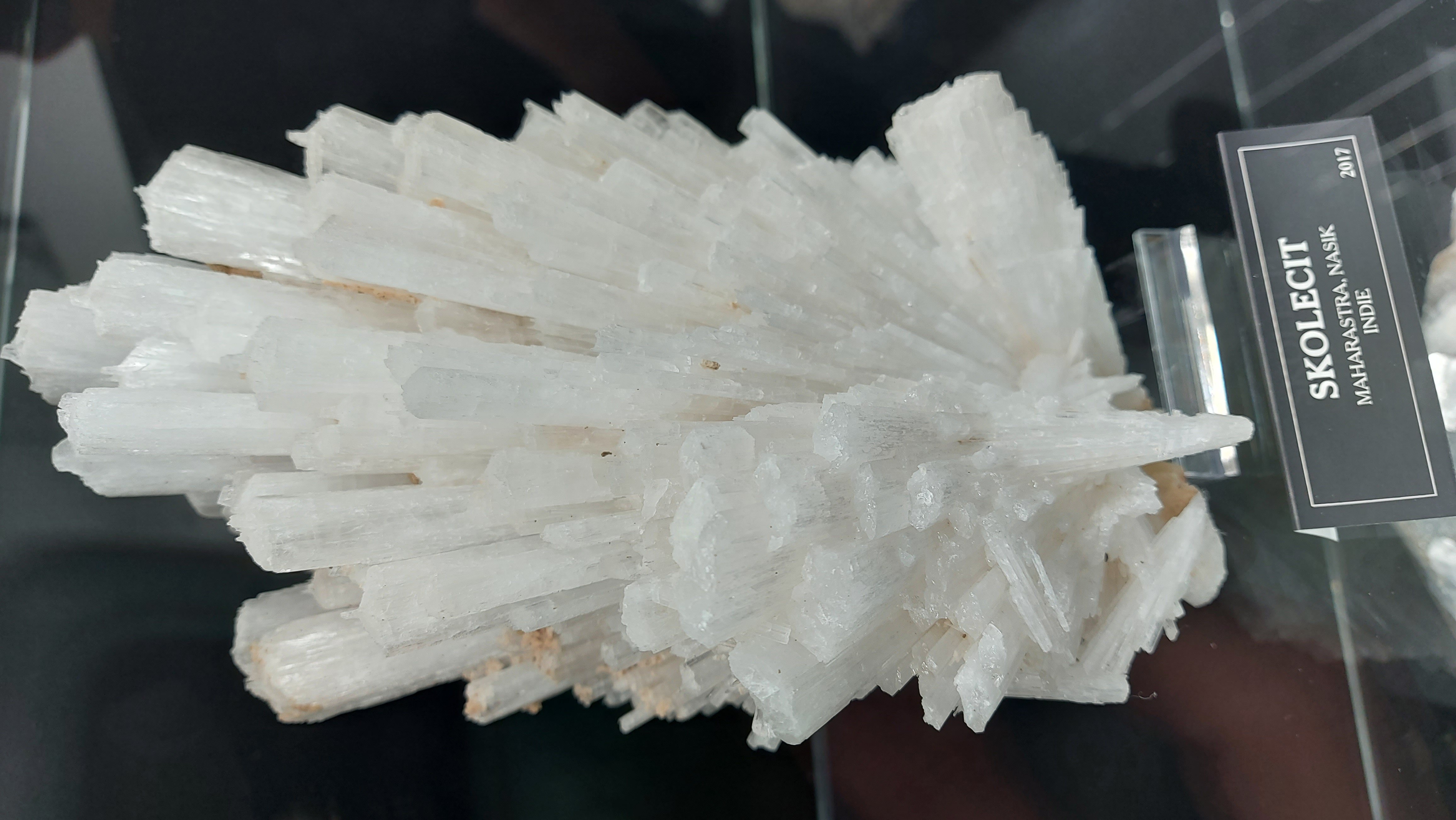 Radiating spray of white scolecite needle crystals on basalt matrix