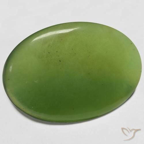 Polished green serpentine cabochon showing translucent apple green on neutral background