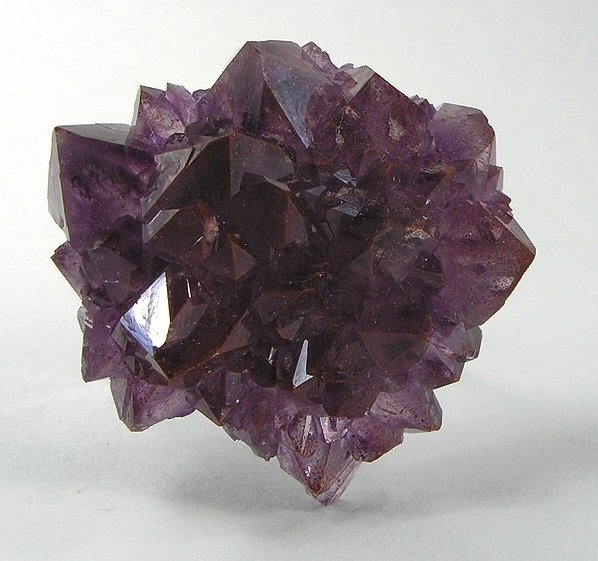 Strawberry quartz crystal or sphere with pink-red iron oxide inclusions on neutral background