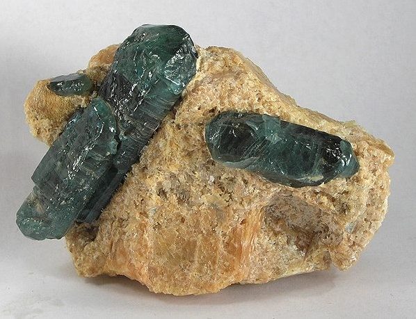 Teal apatite crystal cluster or faceted stone showing vivid neon teal-blue color on white background