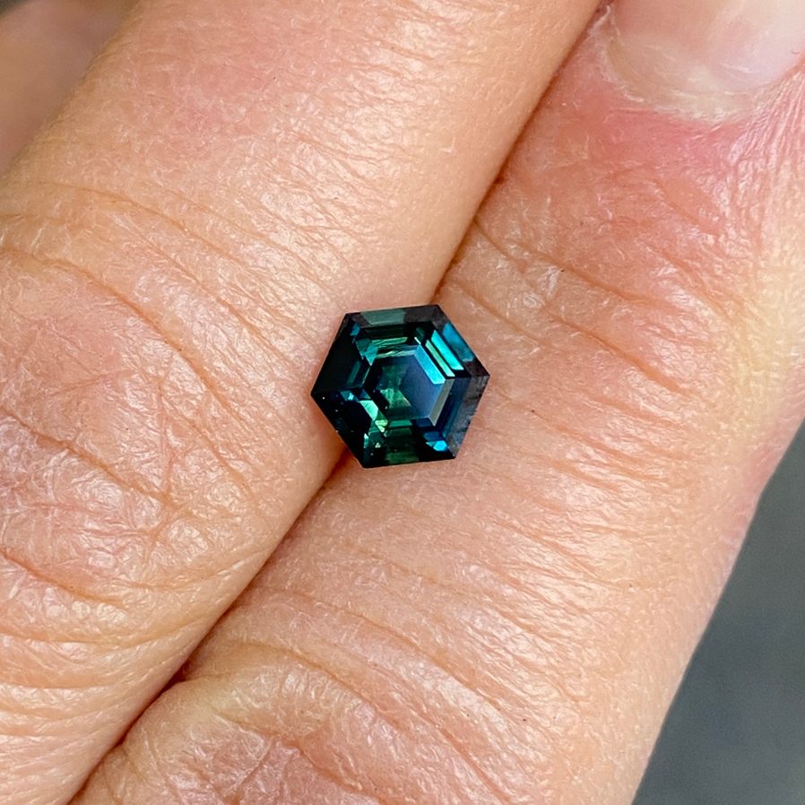 Teal sapphire faceted gemstone showing vivid blue-green color