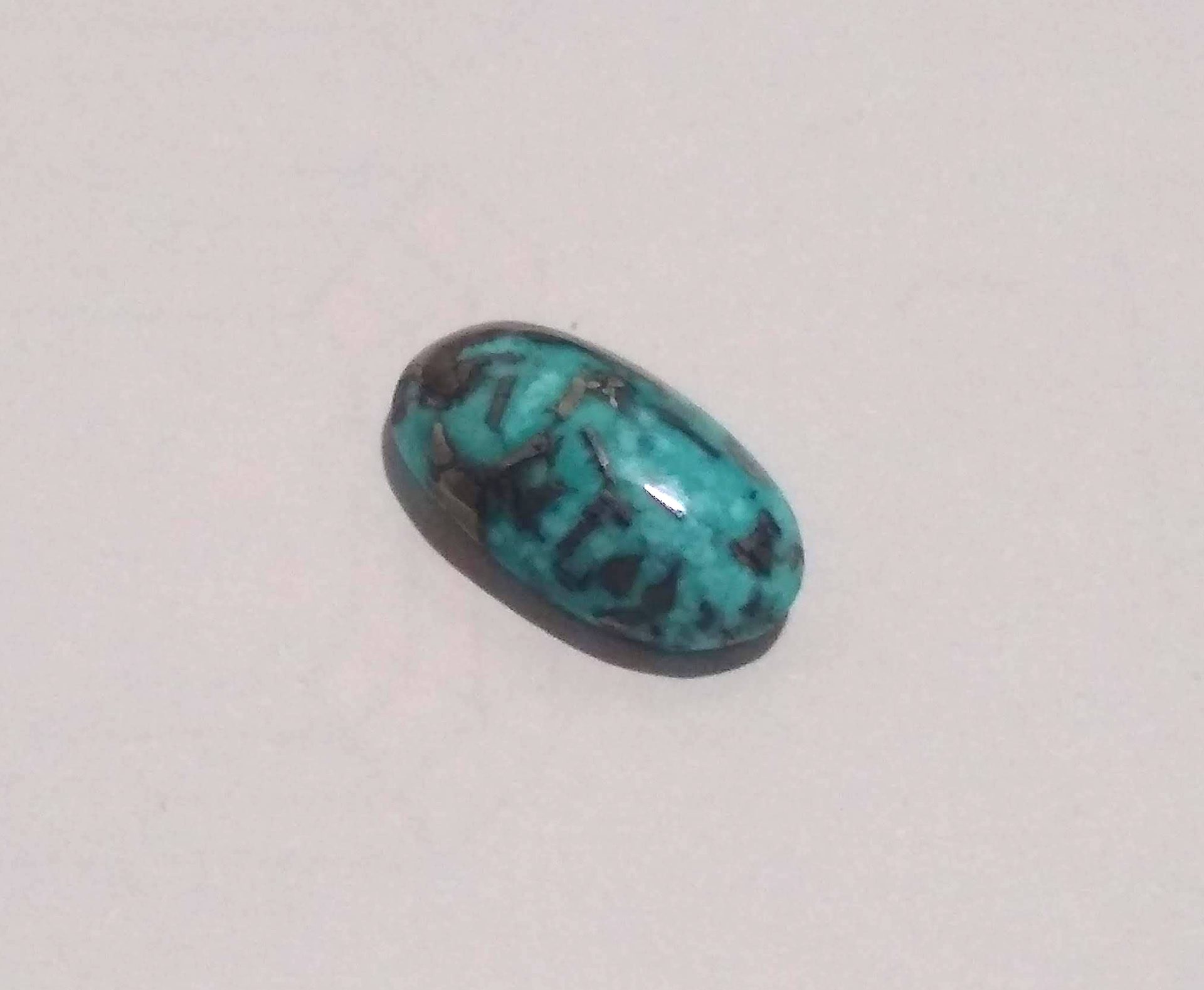 Turquoise matrix cabochon showing vivid blue-green turquoise with dark brown and black spider-web host rock veining